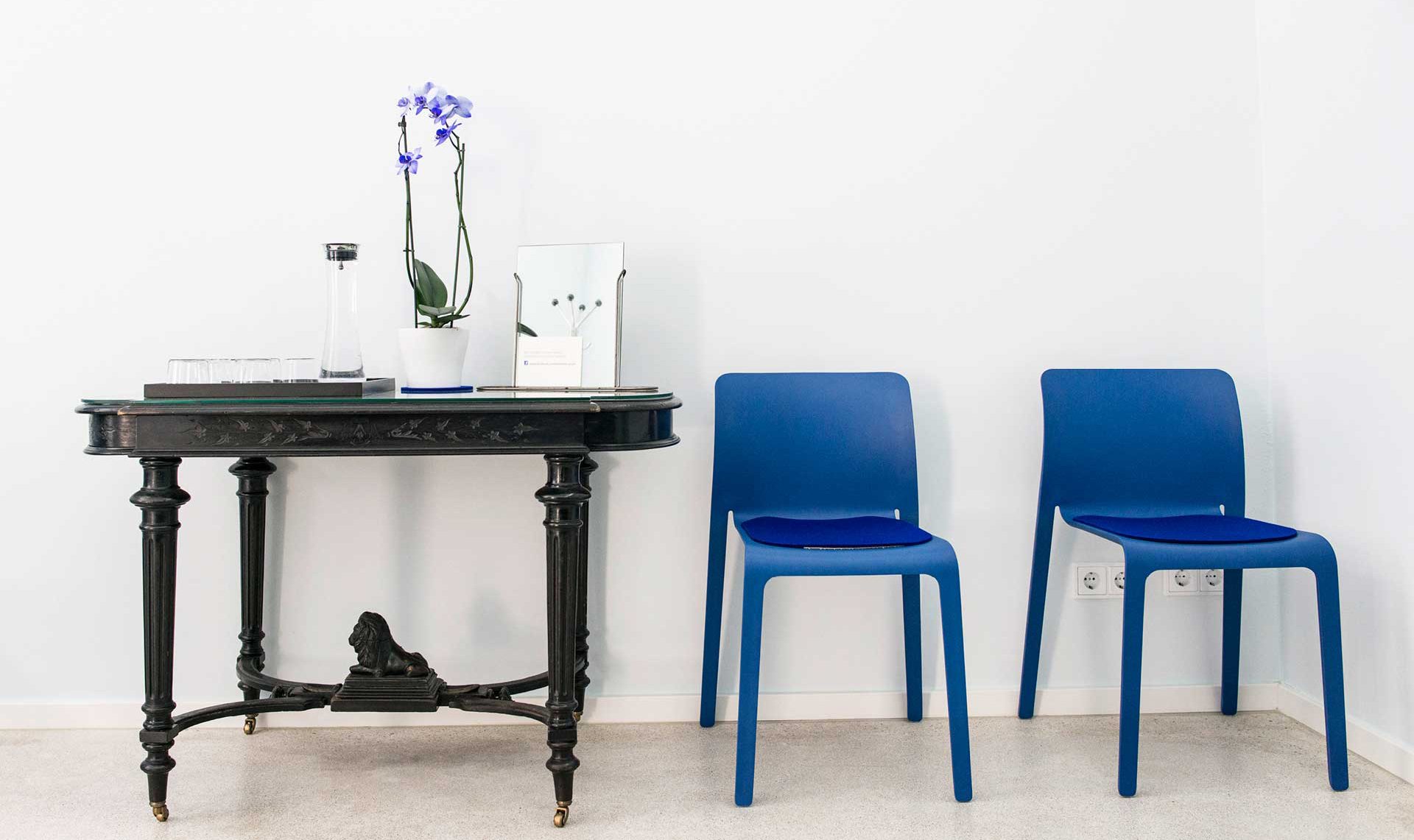 Dr. Peter Merkle, Wartezimmer mit blauen Stühlen und Tisch mit Kunstbüchern 
